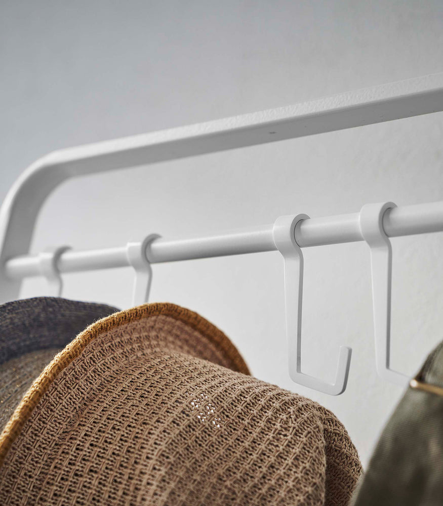 View 7 - Close up of hats hung on hooks included with white Yamazaki Home Coat Rack with Hat Storage