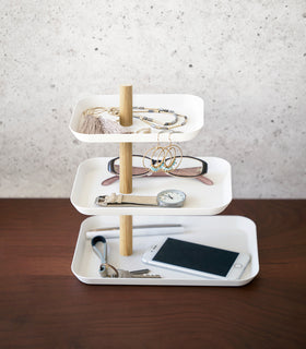 Side view of Yamazaki Home White Rin Series 3-Tiered Accessory Tray with accessories displayed such as a phone or glasses view 3