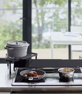 Front view of Black Corner Riser holding pot next to kitchen stovetop by Yamazaki Home. view 8