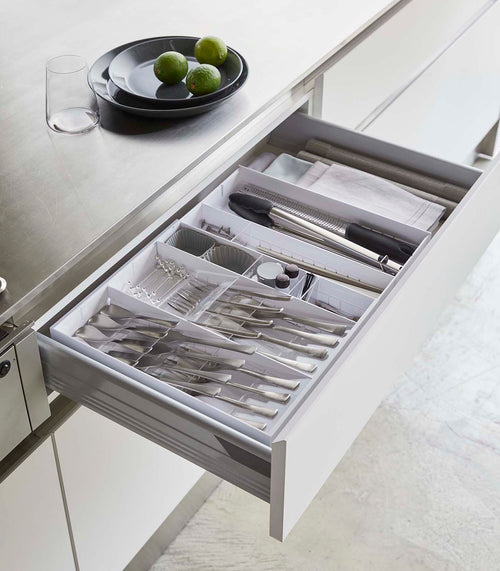 White Expandable Cutlery Storage Organizer holding utensils in kitchen drawer by Yamazaki Home.