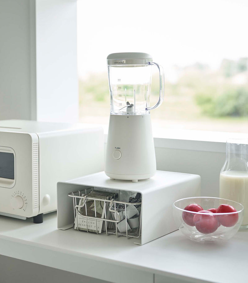 White Yamazaki Home Stackable Countertop Shelf with a blender above and a basket underneath