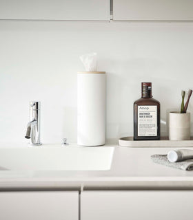 Large White Yamazaki Home Round Tissue Case on a bathroom sink counter view 23