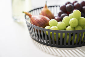 Close up view of black Fruit Basket holding grapes and figs on white tabletop by Yamazaki Home. view 8