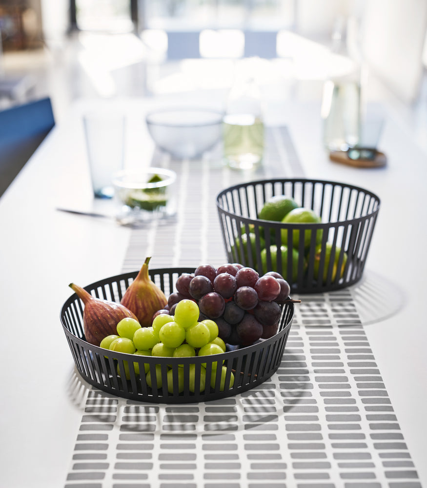 View 18 - Front view of black Fruit Basket holding fruit on dining table by Yamazaki Home.