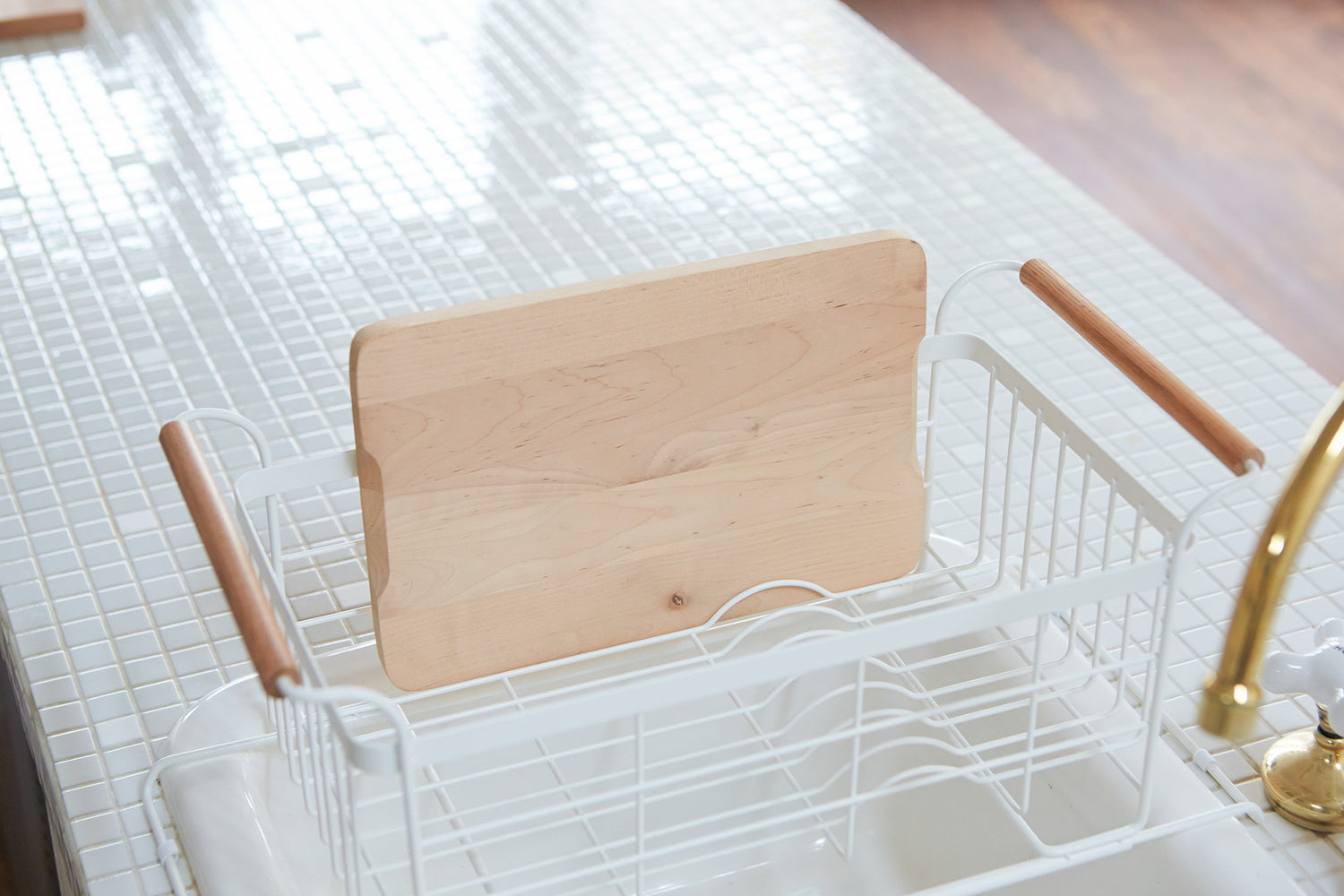 View 5 - White Over-the-Sink Expandable Dish Drying Rack holding cutting board in kitchen by Yamazaki Home.