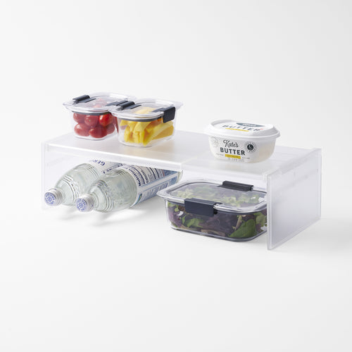 Yamazaki Home Expandable Refrigerator Riser Shelf with props, set against a white background.