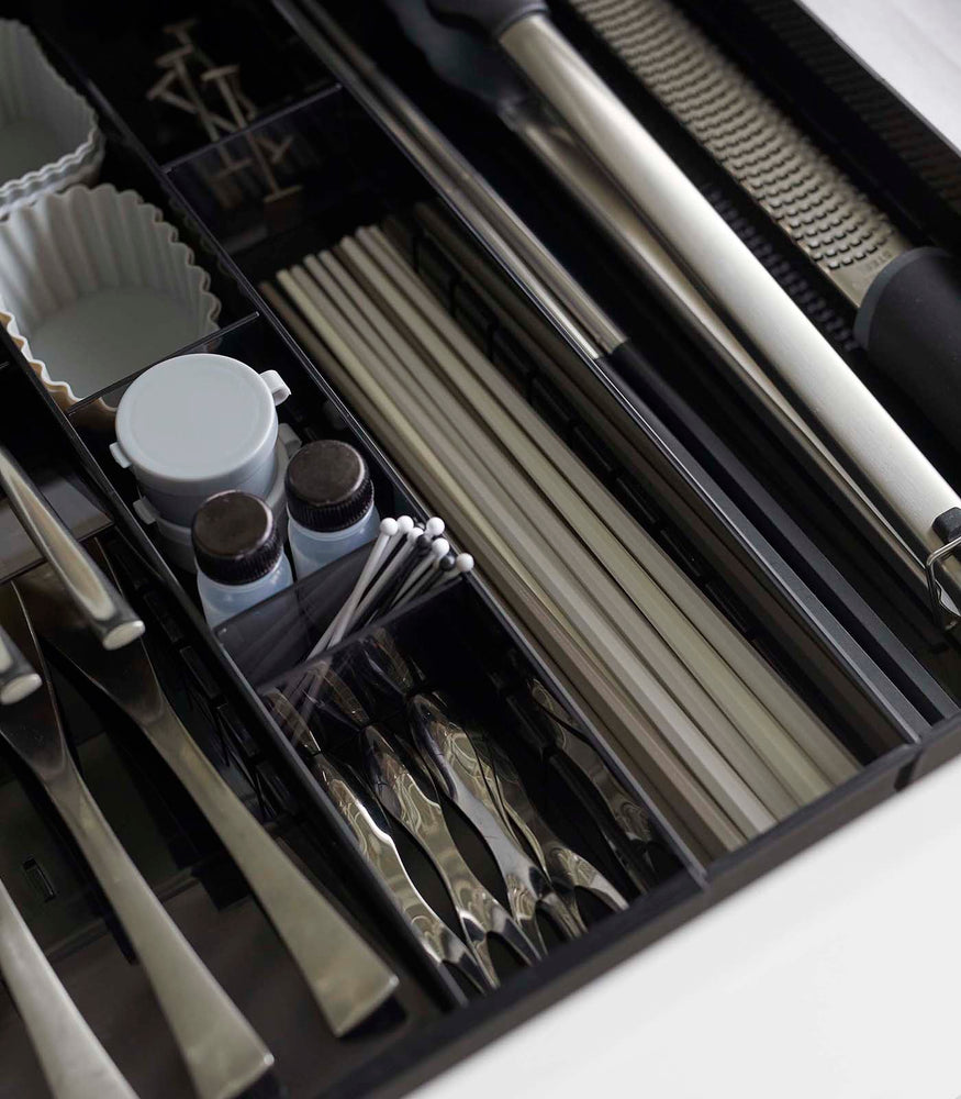 View 23 - Close up aerial view of black Expandable Cutlery Storage Organizer holding utensils by Yamazaki Home.