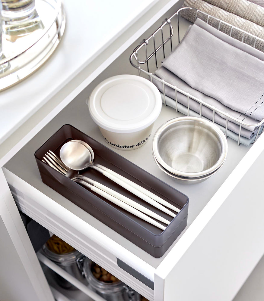 View 40 - Two large stackable clear organizers in black are placed in a kitchen drawer, organizing cutlery, neatly stacked together.