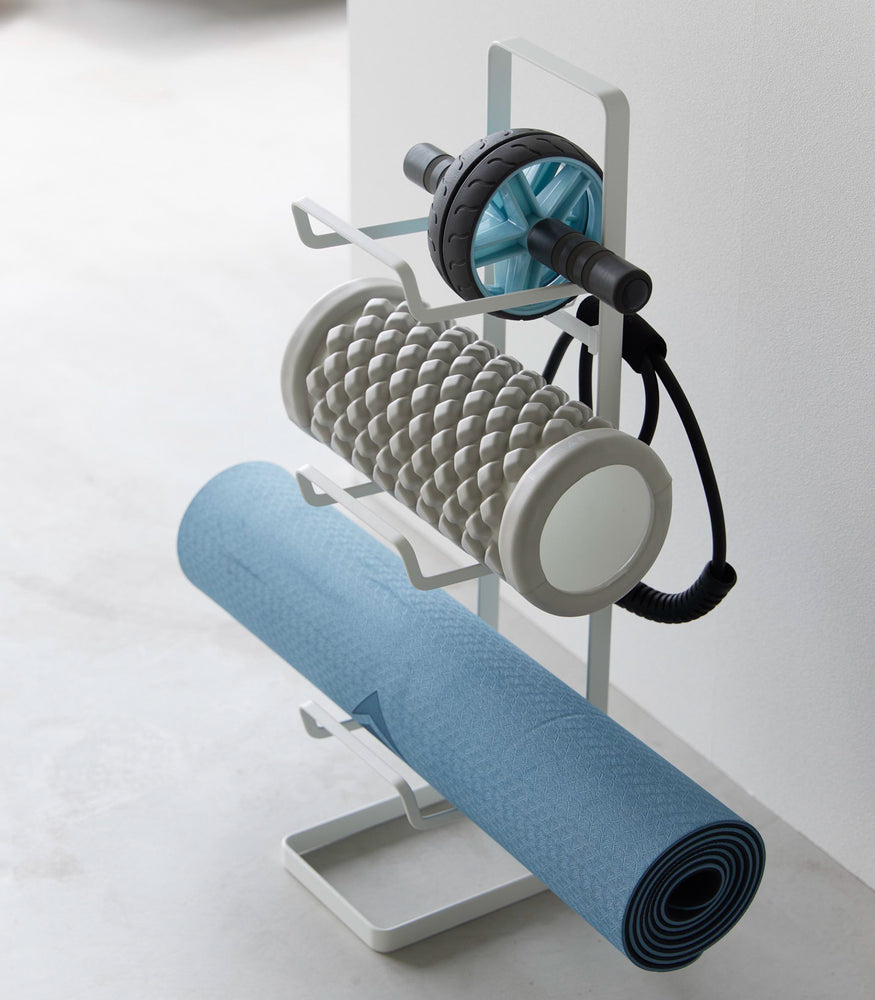 View 5 - Aerial view of Yamazaki Home White Fitness Equipment Storage Rack holding a yoga mat and foam rollers.