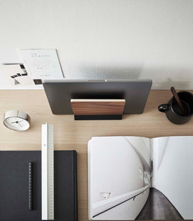 A minimalist wooden laptop stand rests atop an organized desk, viewed from above. view 14