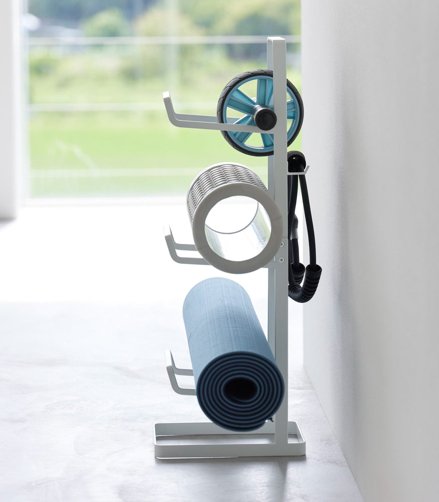 View 8 - Side view of Yamazaki Home Fitness Equipment Storage Rack holding a yoga mat and foarm rollers.