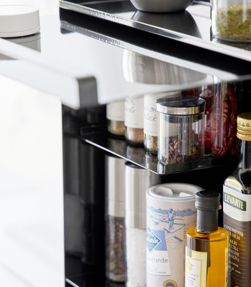 View 13 - Close-up image of the Concealable Spice Rack by Yamazaki Home in black with the front panel open showing various spices inside.