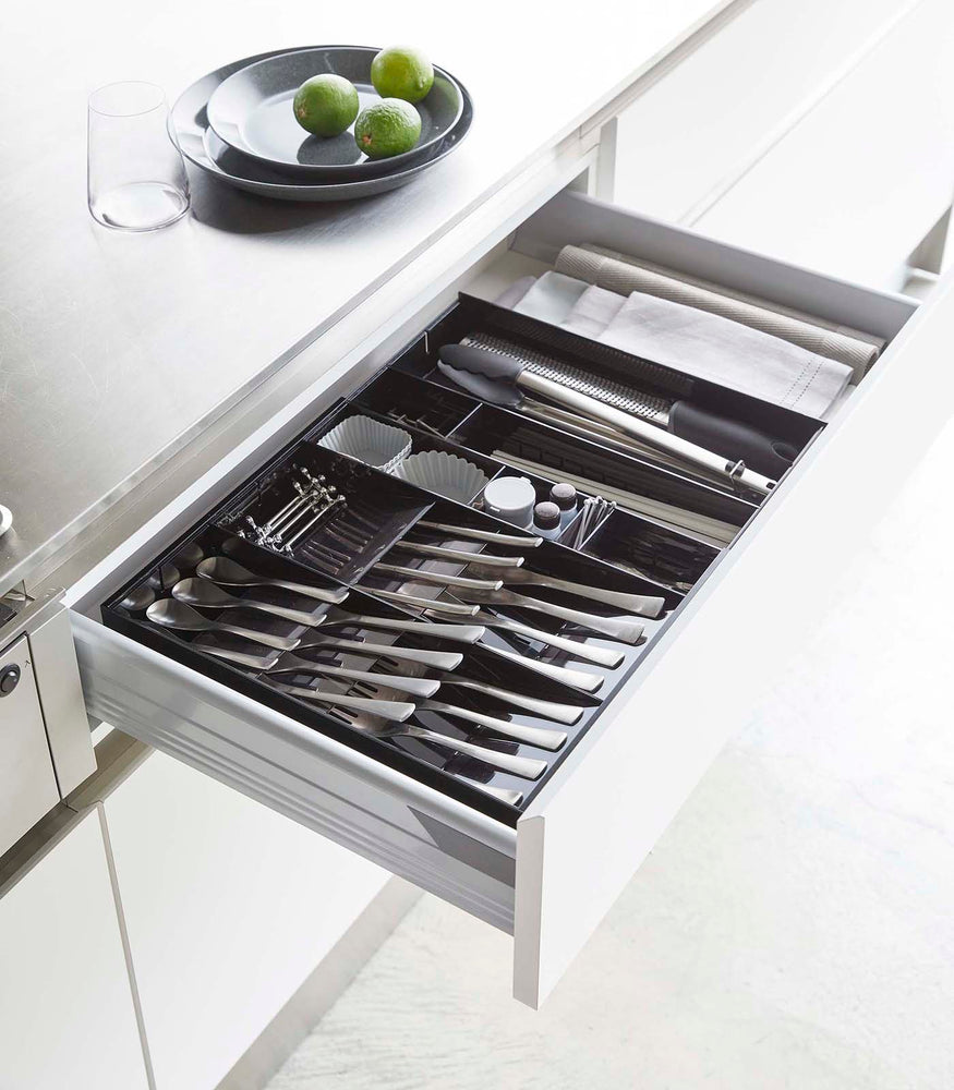 View 21 - Black Expandable Cutlery Storage Organizer holding utensils in kitchen by Yamazaki Home.