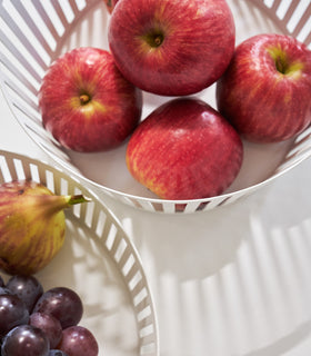 Close up aerial view of white Fruit Basket holding apples and fruit on white background by Yamazaki Home. view 4