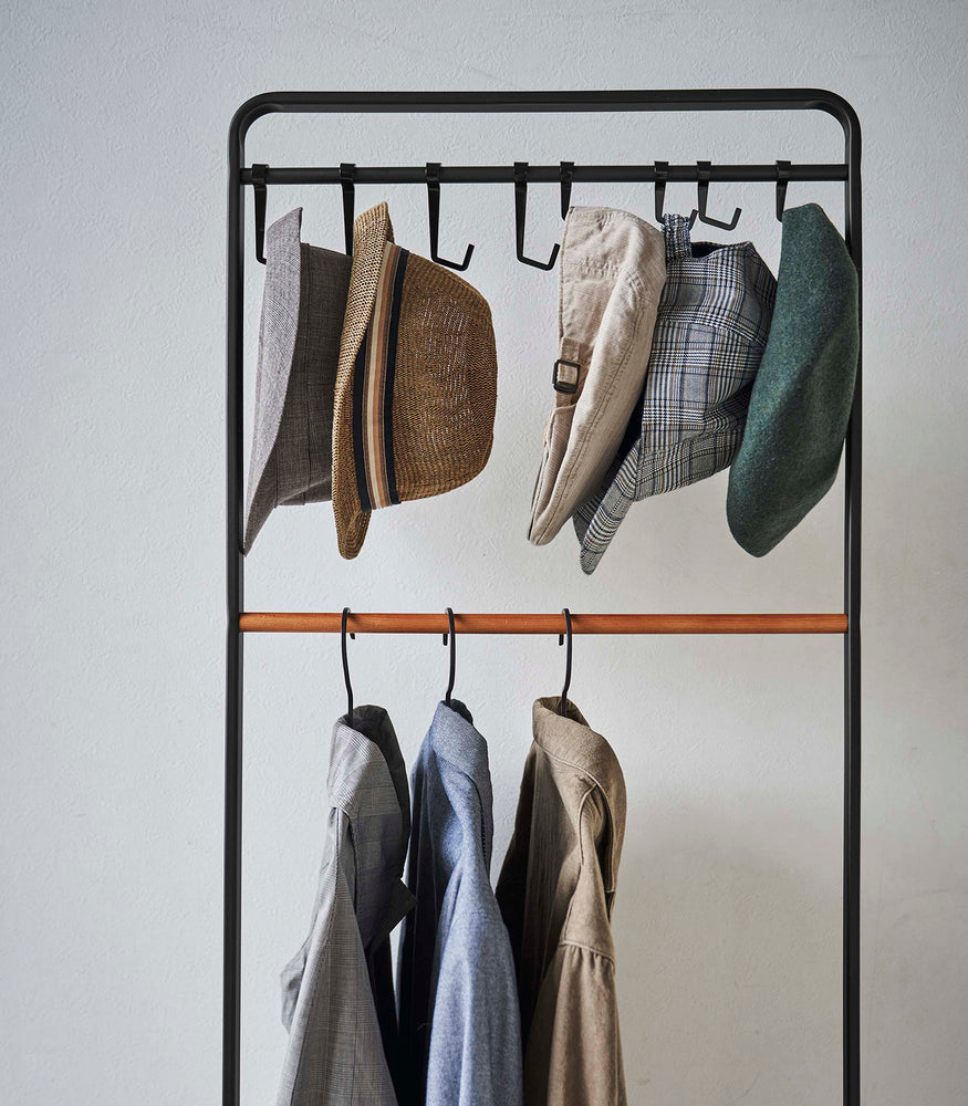 View 11 - Frontal view of clothes and hats hung on black Yamazaki Home Coat Rack with Hat Storage