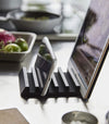 Side view of black Phone and Tablet Stand holding phone and tablet on kitchen countertop by Yamazaki Home.