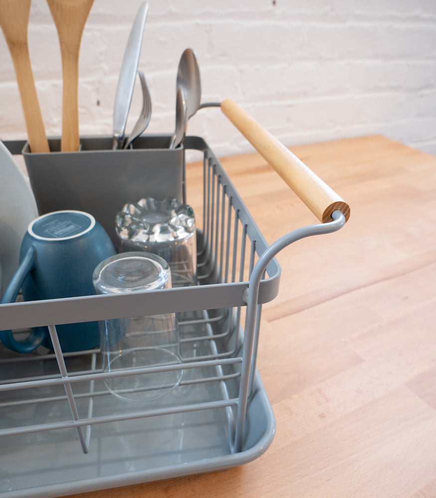 View 13 - Close up of gray wooden handle Dish Rack holding cups and silverware by Yamazaki Home.