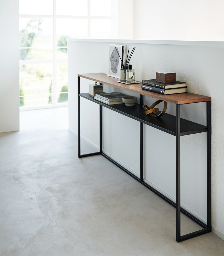 View 27 - Black Yamazaki Home Long Console Table - Shelf against a wall with books and decorations on it