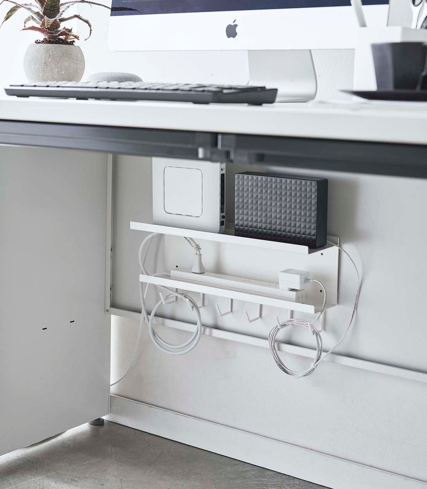 View 3 - White Wall-Mount Cable and Router Storage Rack holding routers and power cord under desk by Yamazaki Home.