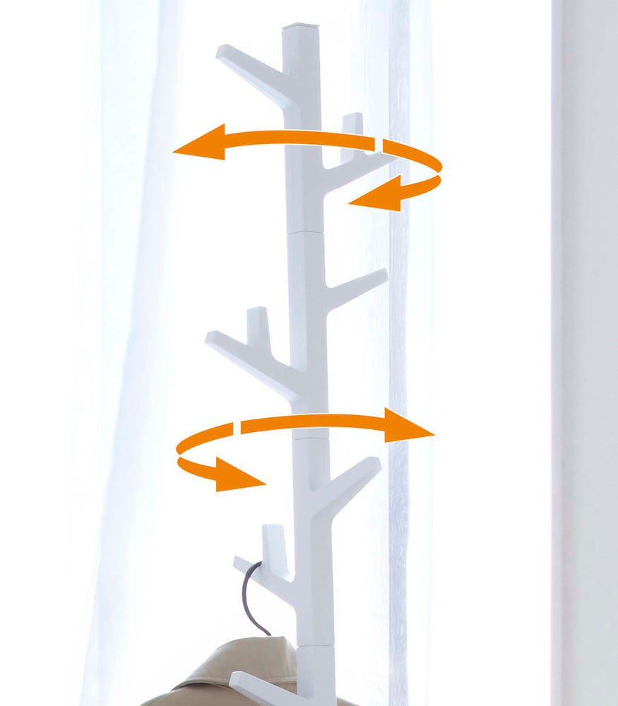 View 5 - White coat rack in the shape of a tree, marked with arrows to show the movement of the rack.