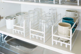 Close up of 3 Yamazaki Home white Glass and Mug Cabinet Organizers on a shelf view 6