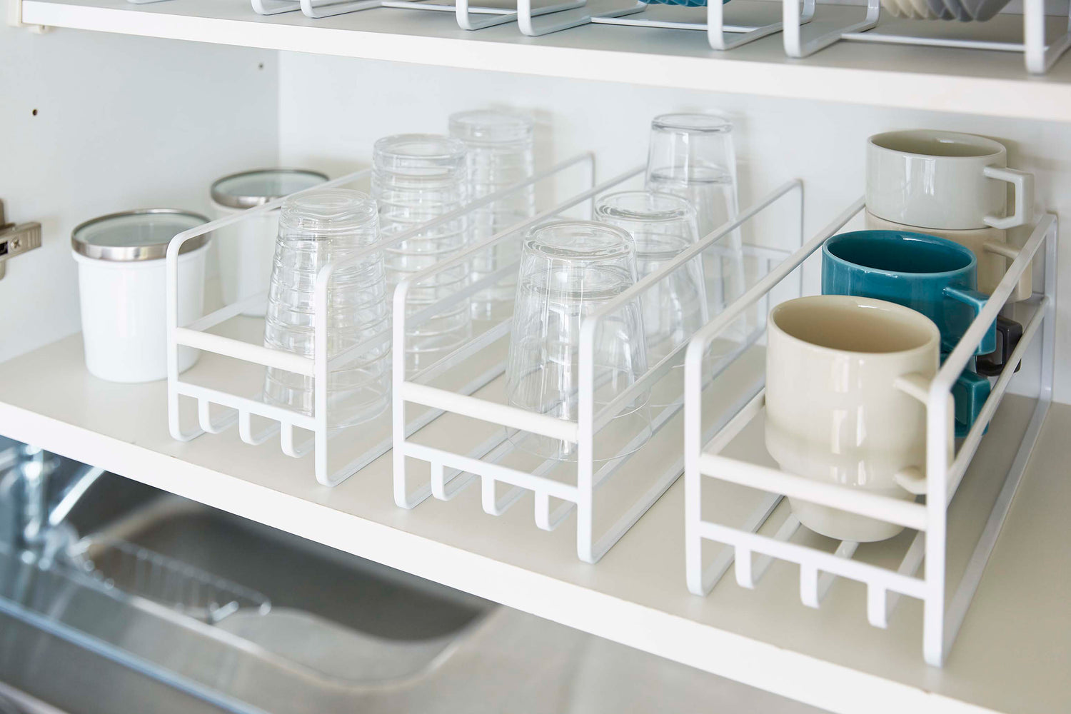 View 5 - Close up of 3 Yamazaki Home white Glass and Mug Cabinet Organizers on a shelf