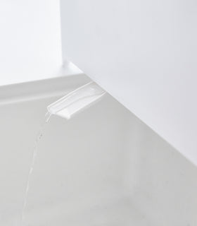 Close up of white Slim Dish Rack water spout draining into sink by Yamazaki Home. view 7