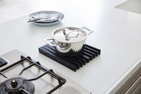 Black Folding Dish Drainer Mat holding pot on kitchen countertop by Yamazaki Home. view 9