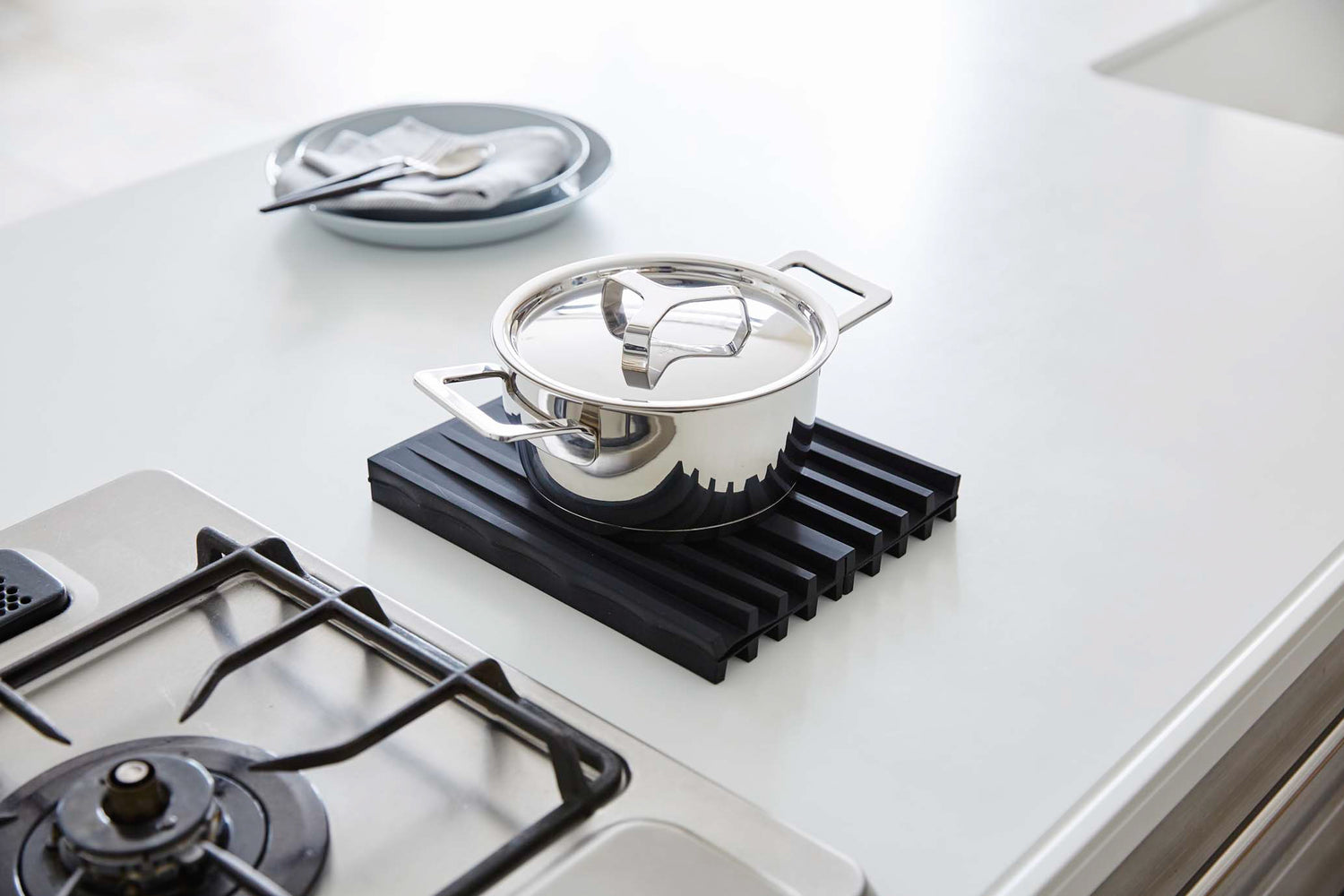 View 9 - Black Folding Dish Drainer Mat holding pot on kitchen countertop by Yamazaki Home.
