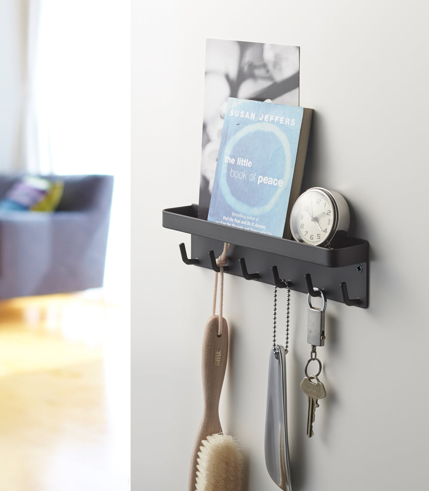 View 9 - Black Magnetic Key Rack with Tray holding book, clock, and key on wall by Yamazaki Home.