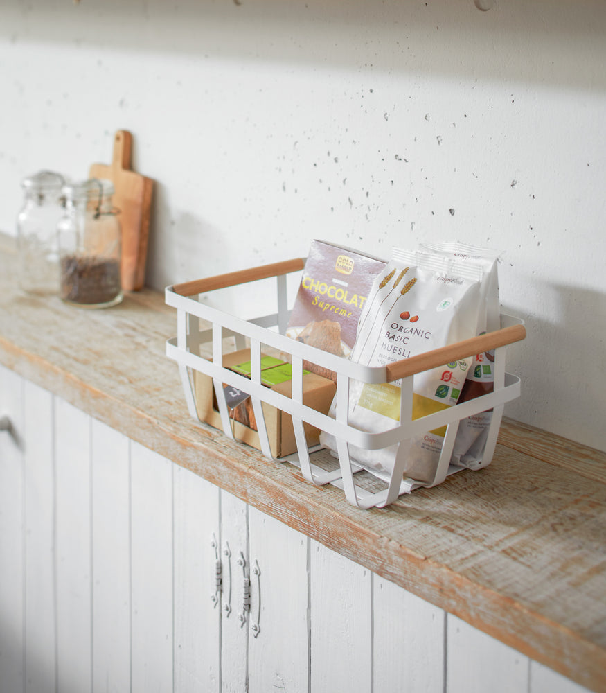 View 8 - White storage basket holding food items on shelf by Yamazaki Home.