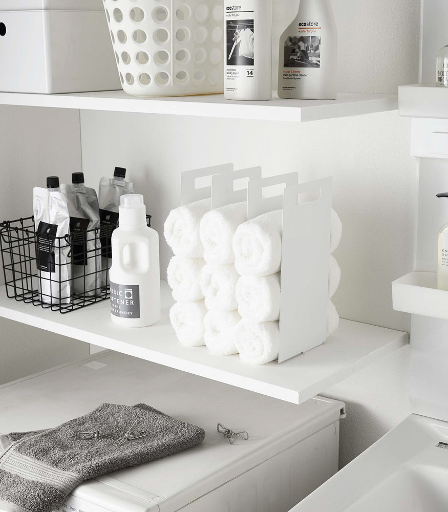 View 2 - White Towel Storage Organizer displaying towels on laundry room shelf by Yamazaki Home.