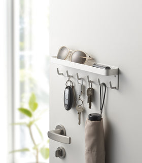 White Magnetic Key Rack with Tray holding keys, umbrella, and sunglasses on door by Yamazaki Home. view 2
