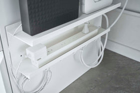 Close up view of white Wall-Mount Cable and Router Storage Rack holding routers and power cord under desk by Yamazaki Home. view 4