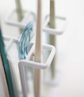 Close up view of white Toothbrush Holder on mirror by Yamazaki Home. view 3