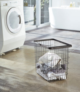 Black Wire Laundry Basket holding clothes in laundry room by Yamazaki Home. view 4