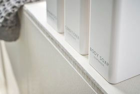Close up bottom view of Yamazaki Home white Shampoo, Conditioner, and Body Soap dispensers. view 6