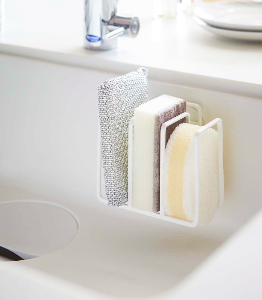 View 3 - White Sponge Holder containing sponges in kitchen sink by Yamazaki Home.