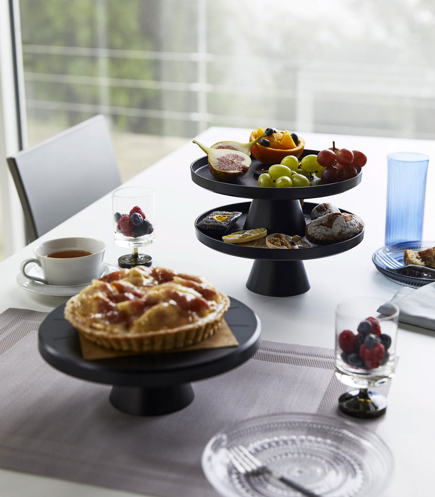 View 11 - Black Stackable Serving Stand displaying food items on dining table by Yamazaki Home.