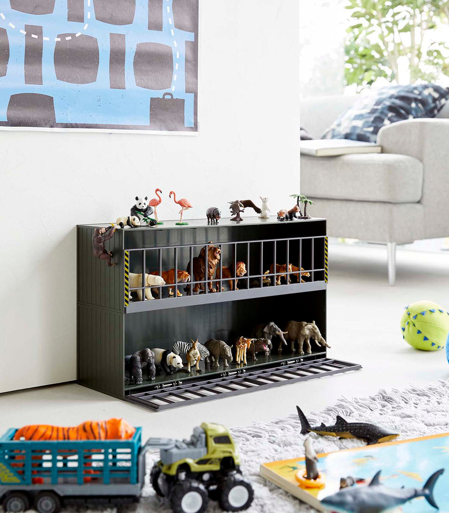 View 13 - Dark green Two-Tier Toy Dinosaur and Animal Storage Rack in living room play area holding toy animals by Yamazaki Home.