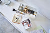 Aerial view of open white Makeup Organizer and comparments holding makeup products on table by Yamazaki Home.
