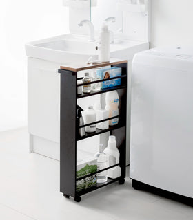 Black Rolling Storage Cart holding cleaning supplies in bathroom by Yamazaki Home. view 12