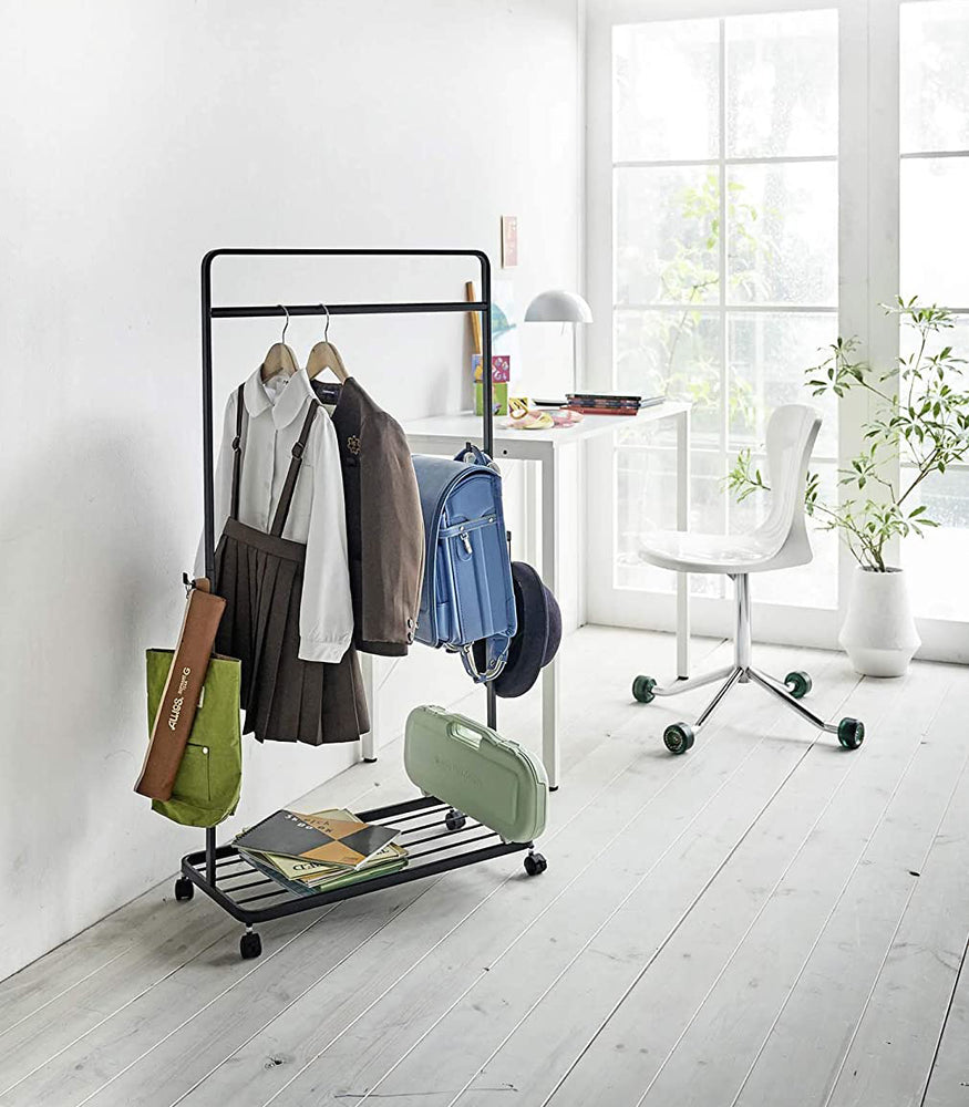 View 8 - Black Rolling Coat Rack holding school uniform, backpack, hat, and school supplies by Yamazaki Home.