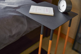 Close up view of black C Side Table holding clock and book in bedroom by Yamazaki Home. view 9