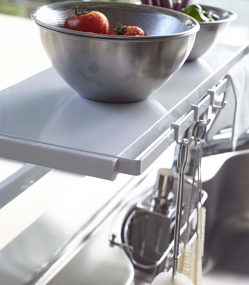 View 7 - Close up of white Expandable Countertop Organizer displaying bowls and cleaning utensils by Yamazaki Home.