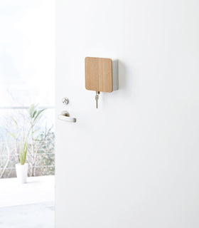 White Square Magnetic Key Cabinet with Hooks holding key on door by Yamazaki Home. view 2
