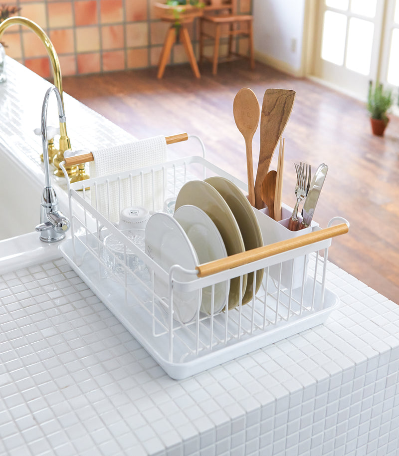 Side aerial view of white Dish Rack on kitchen counter holding clean dinnerware by Yamazaki Home.