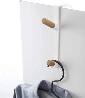 Close up view of white Over-the-Door Hook holding shirt on white background by Yamazaki Home. view 3