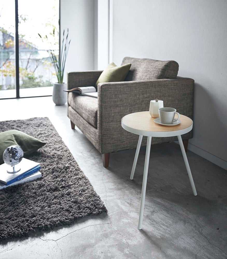 View 3 - White Side Table by Yamazaki Home in a living room holding a cup of coffee and a sugar canister.