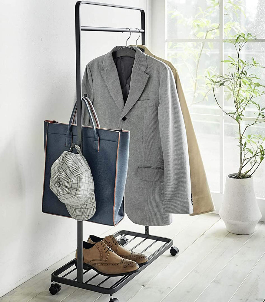 View 10 - Black Rolling Coat Rack holding jackets, bag, hat, and shoes by Yamazaki Home.
